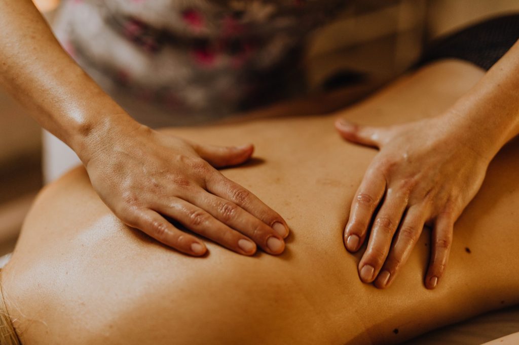 Hands giving a registered massage therapy back treatment, compared with acupuncture